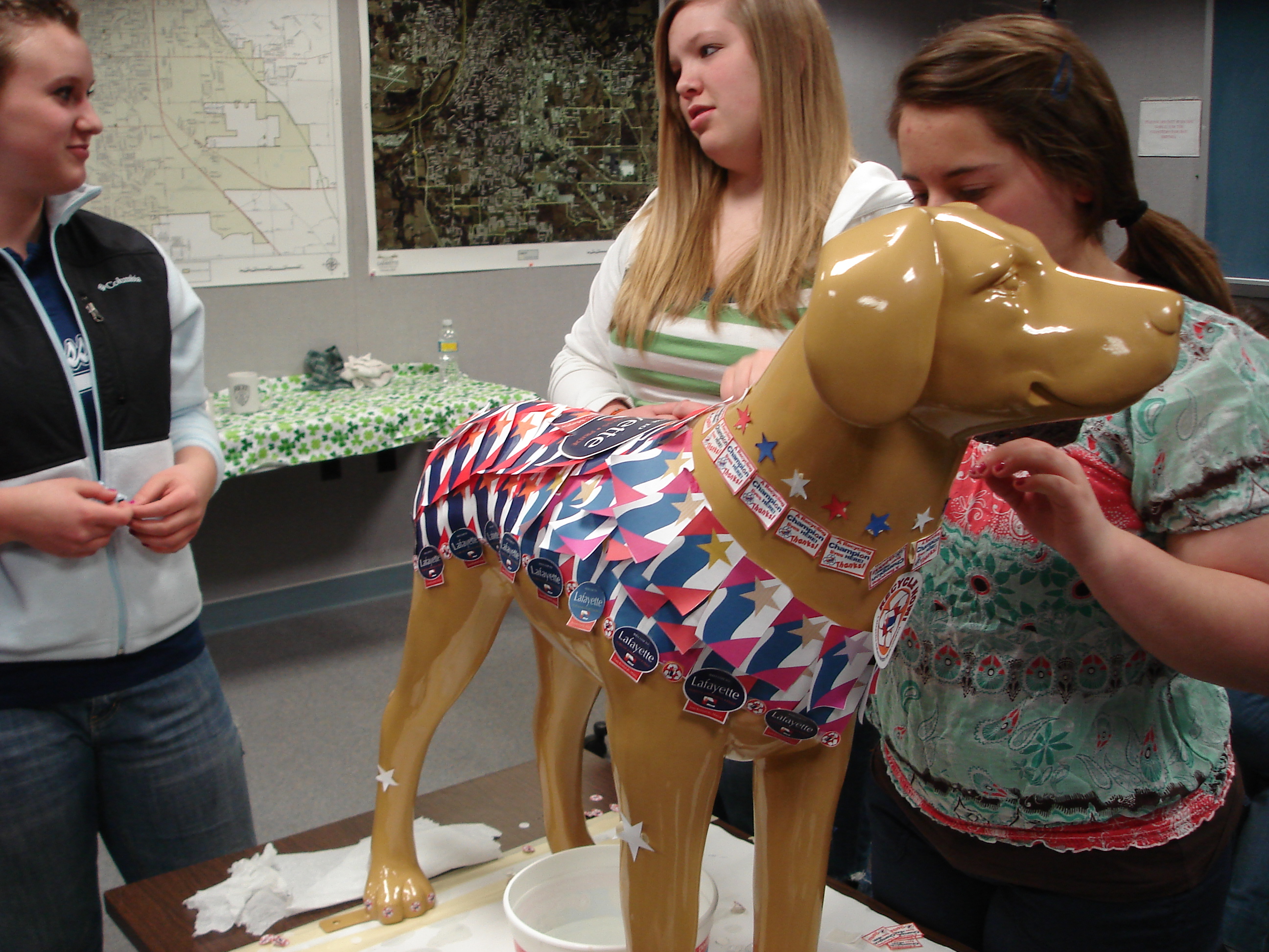 3 teens decorating a fake, plastic dog